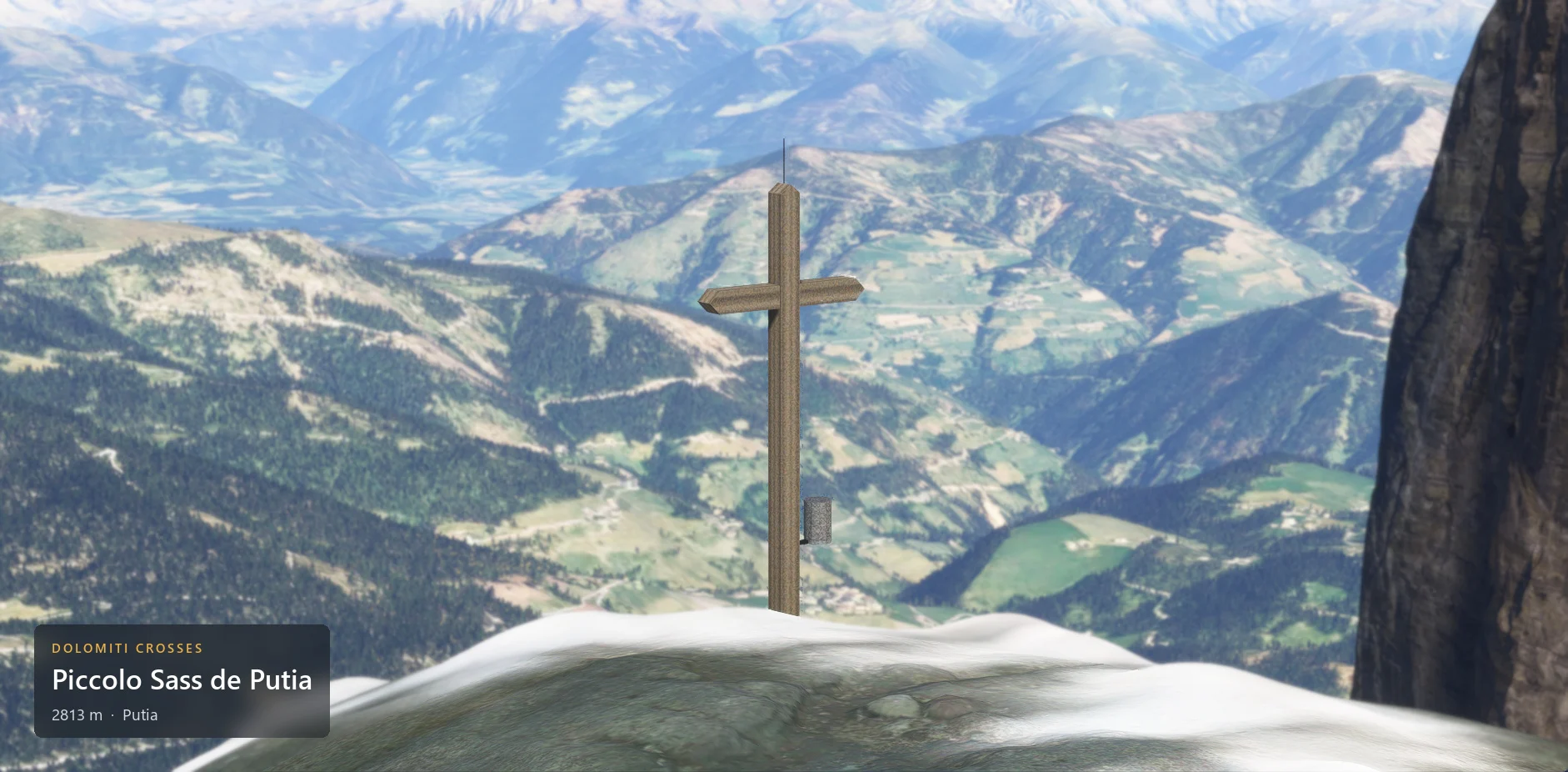 The summit cross on Piccolo Sass de Putia (2813 m) seen from below against the sky, with the caption plate in the lower left corner.