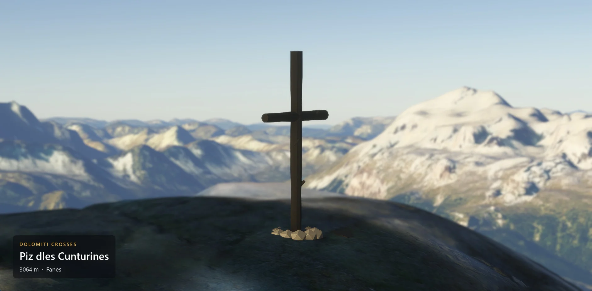 The summit cross on Piz dles Cunturines (3064 m) seen from the side, with the caption plate in the lower left corner.